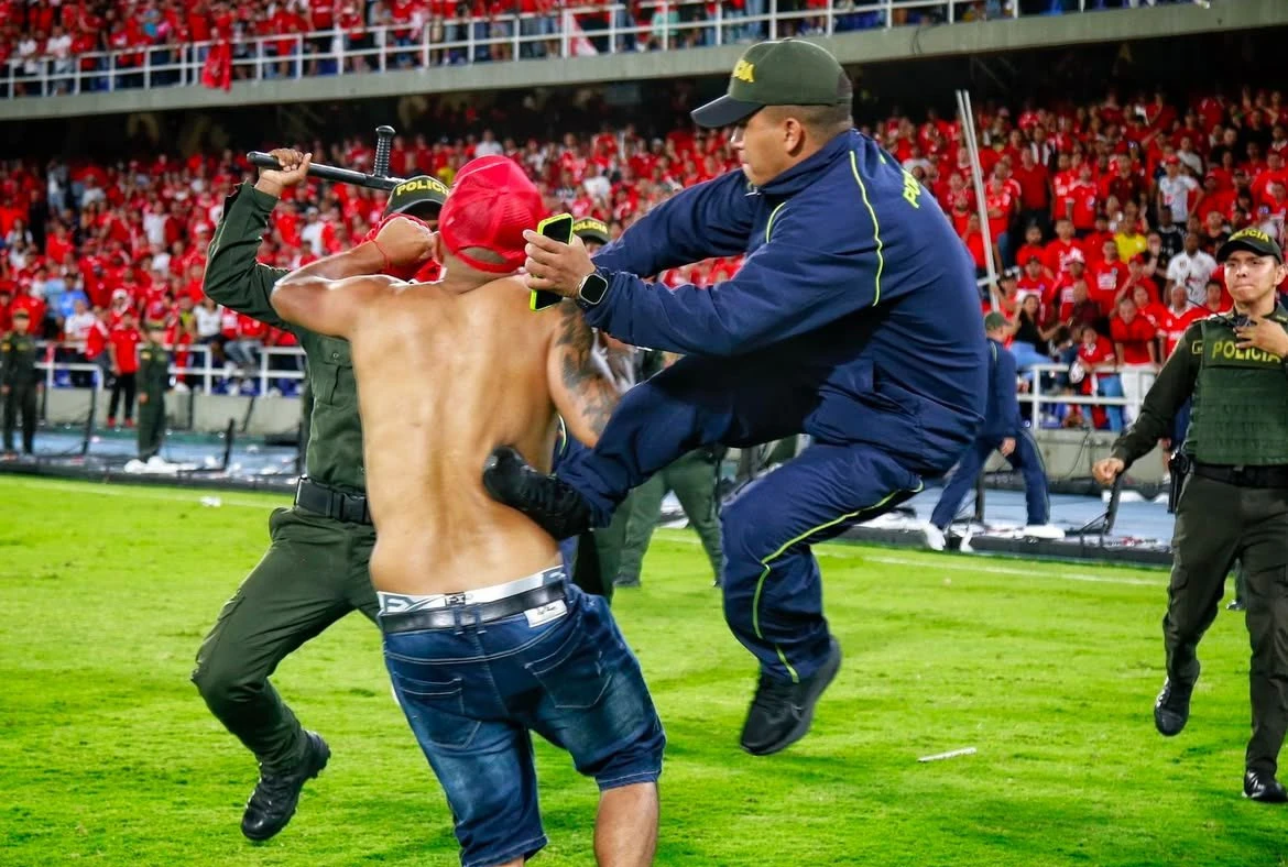 Policías reducen a un barrista que participaba en los desmanes durante el partido entre América y Nacional. Foto: @ParalyticsCOL